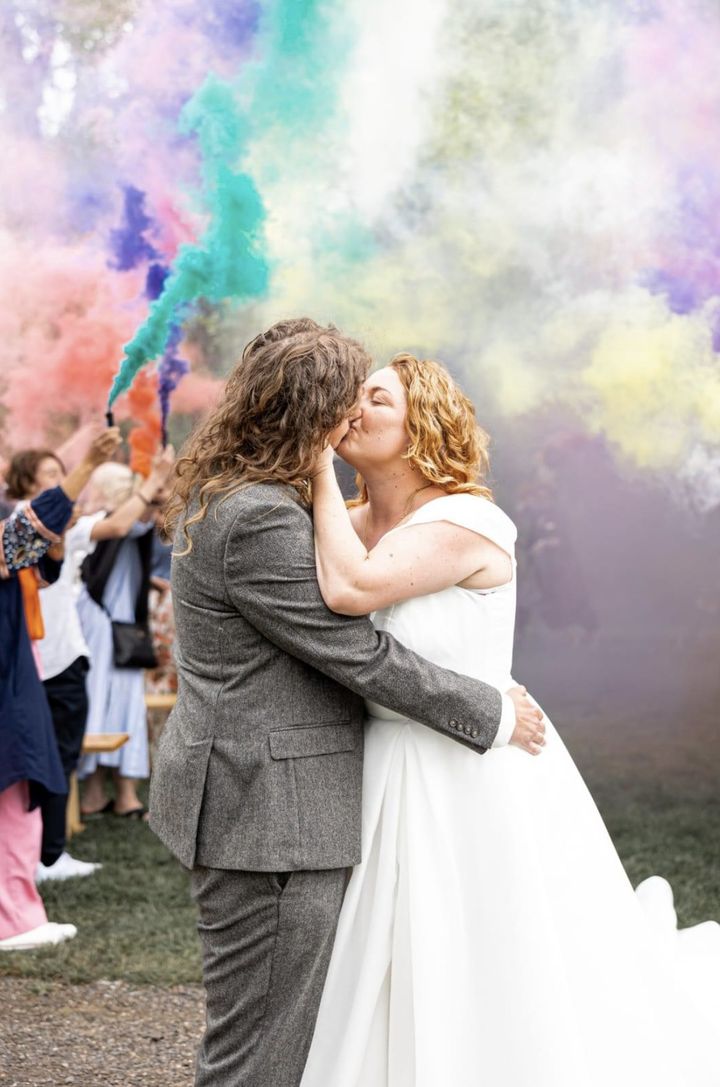 Newlyweds kissing in a cloud of coloured smoke
