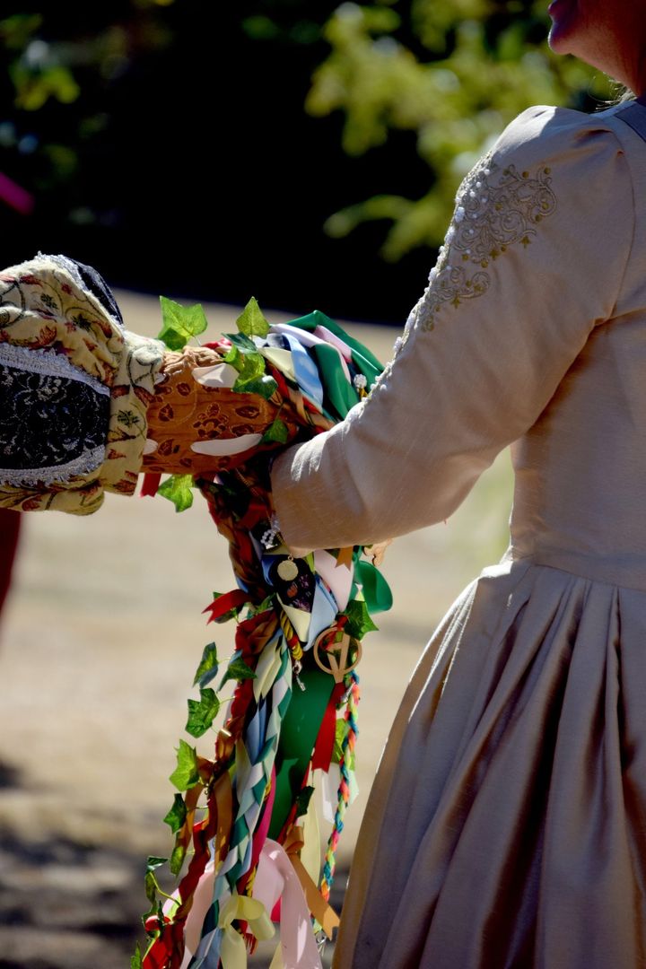 A couple's hands bound with colourful handfasting ribbons