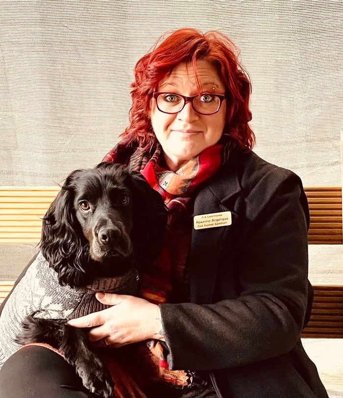 Roxanne smiling, holding Brian, her black cocker spaniel